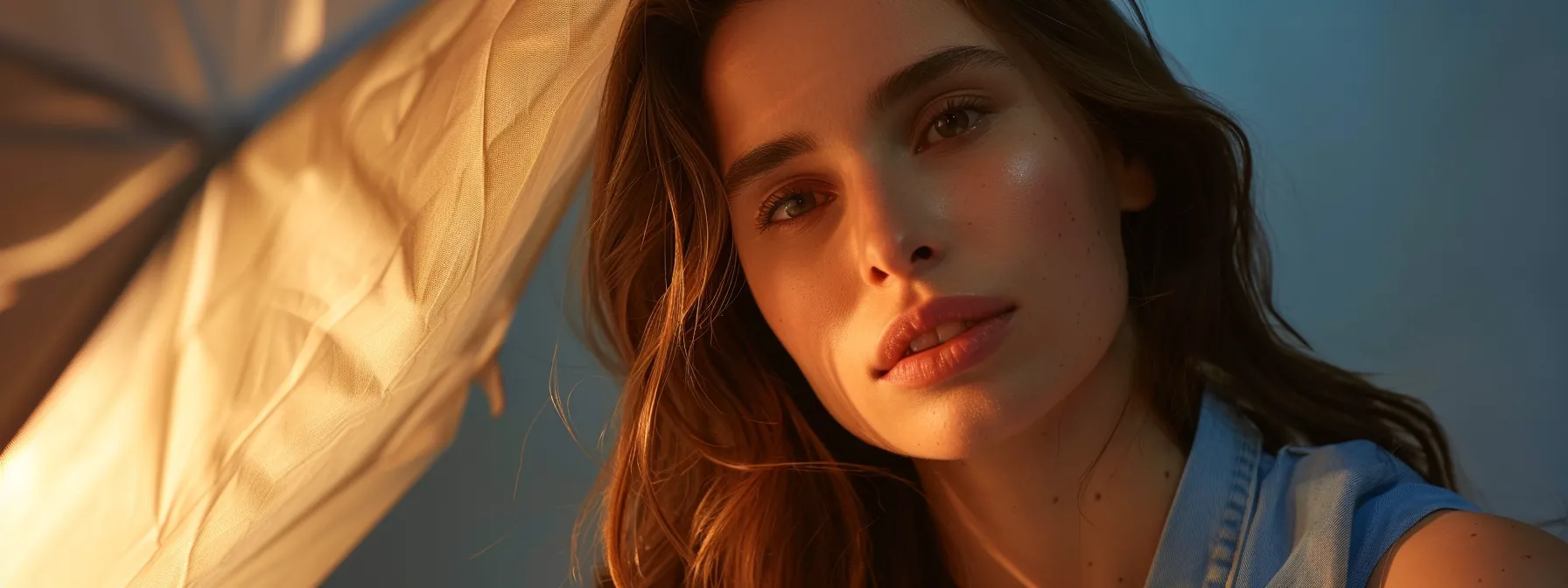 a photographer adjusting a softbox to create a soft, flattering light on a subject's face in a professional studio setting.